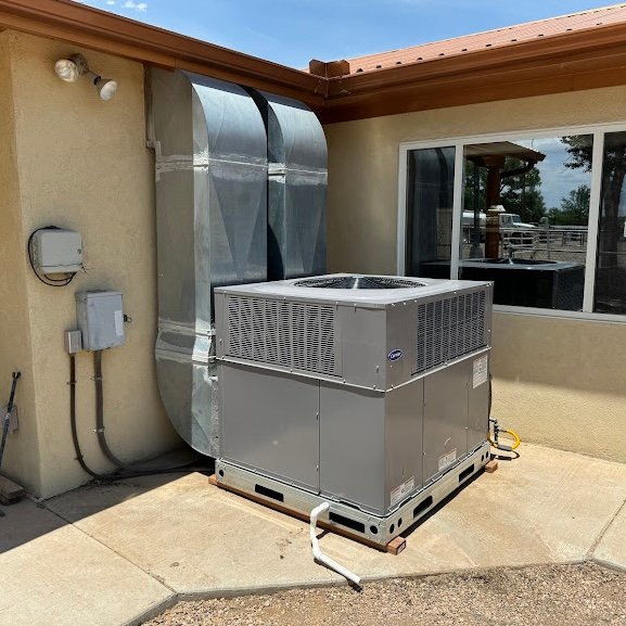 An Air Dynamics of Tulsa technician services an outdoor compressor unit beside a house in Tulsa.